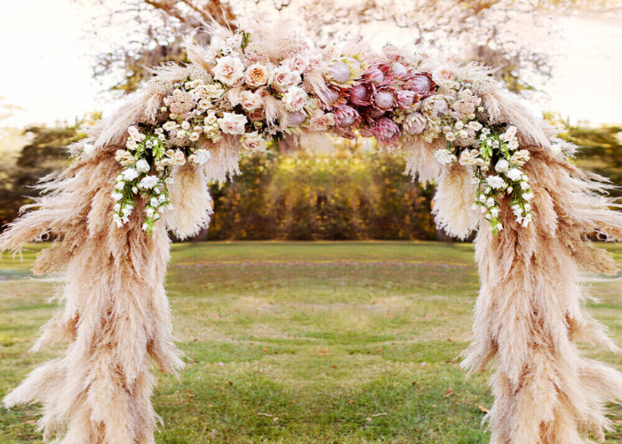 m arranjo delicado de flores secas suspensas em arco, trazendo um charme encantador para um casamento ao ar livre.