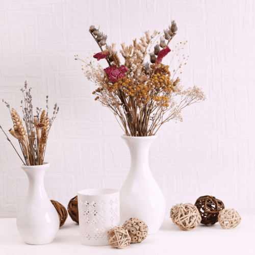 Arranjo floral seco em vaso sobre uma mesa de madeira, exemplo de arte com flores secas